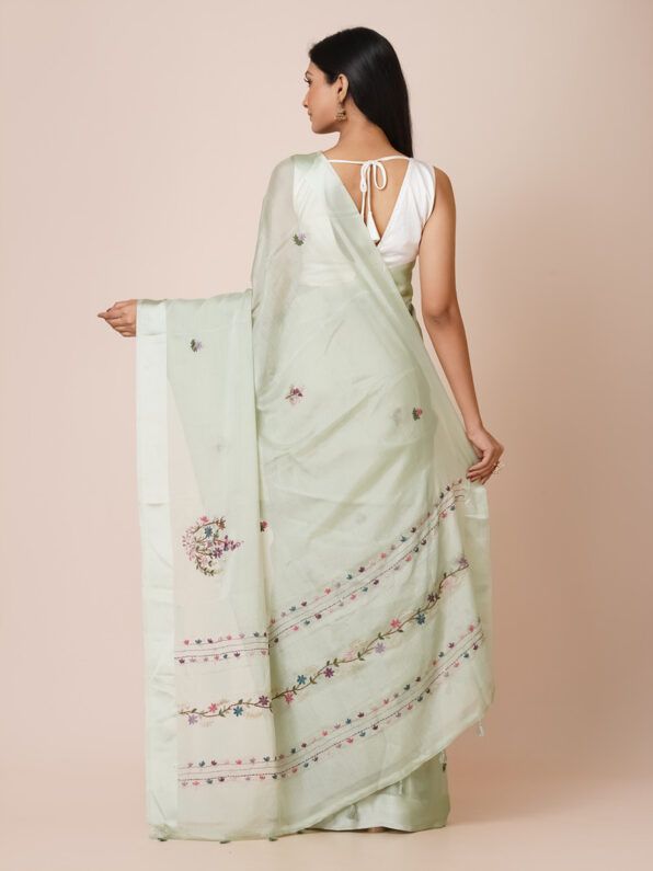 Model wearing a light green pure crepe saree with intricate floral embroidery, perfect for festive occasions